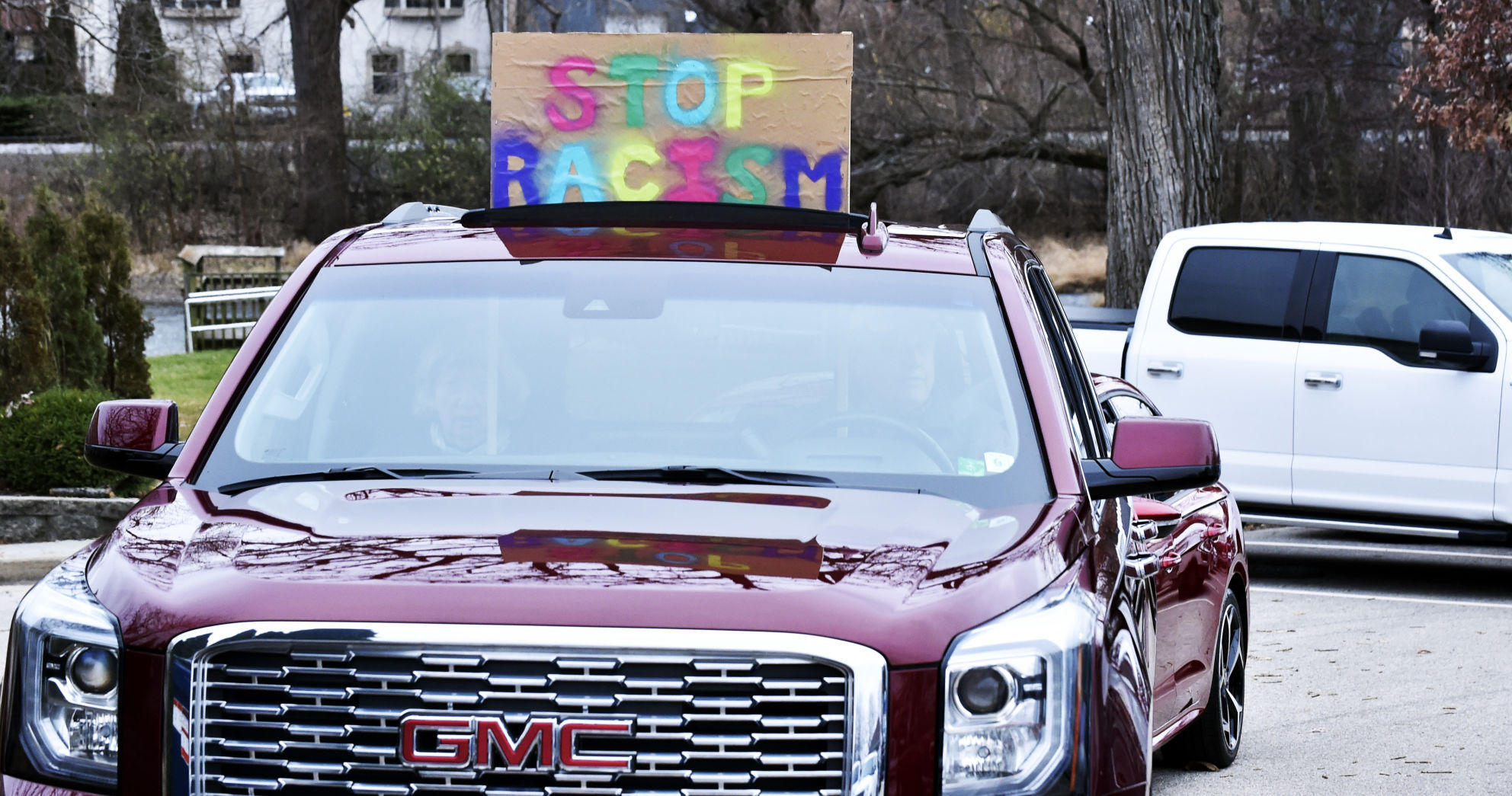 Stop Racism sign held through truck sunroof